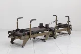 Carriage One full-size reformer with brown upholstery viewed from the opposite end